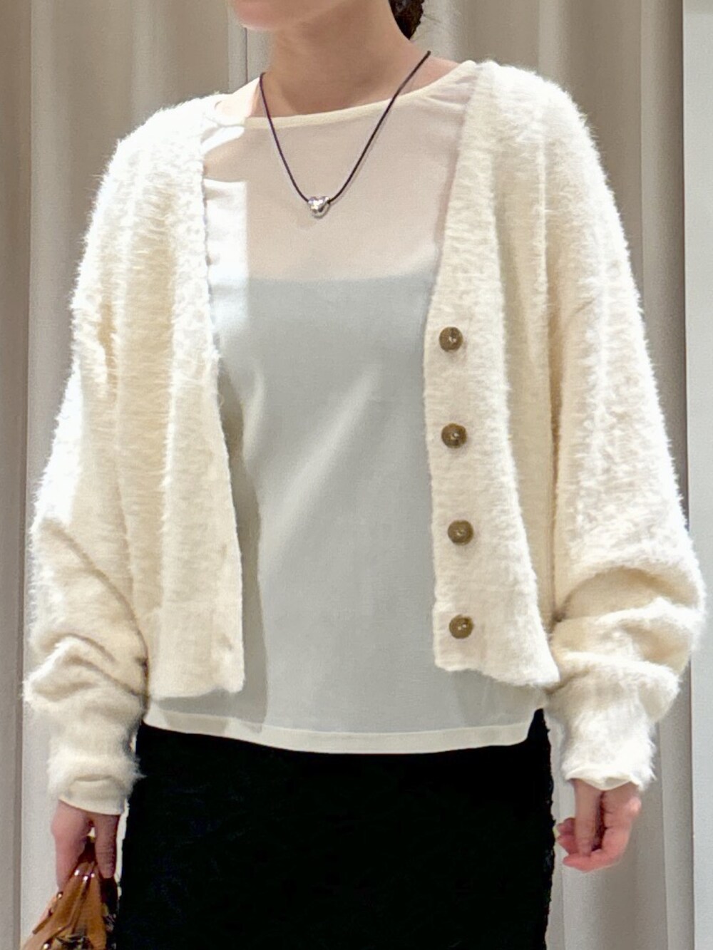 ブラック系のスカート、ベージュ系のショルダーバッグ、ブラック系のブーツを着用したレディースの冬コーディネートの3枚目の写真