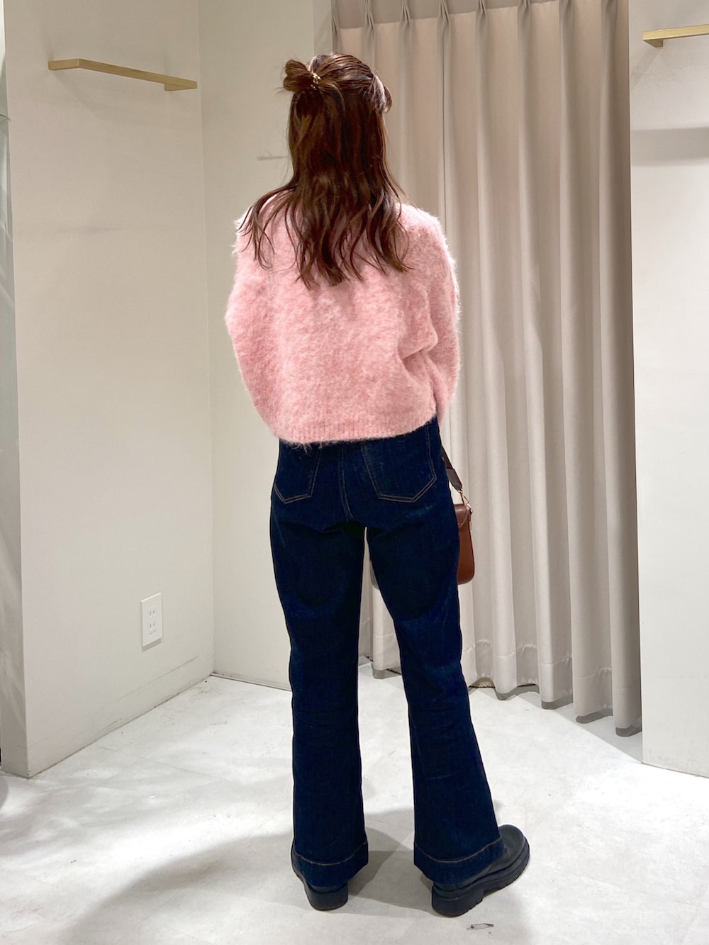 ピンク系のニット/セーター、ブラウン系のショルダーバッグ、ブルー系のデニムパンツを着用したレディースの冬コーディネートの3枚目の写真