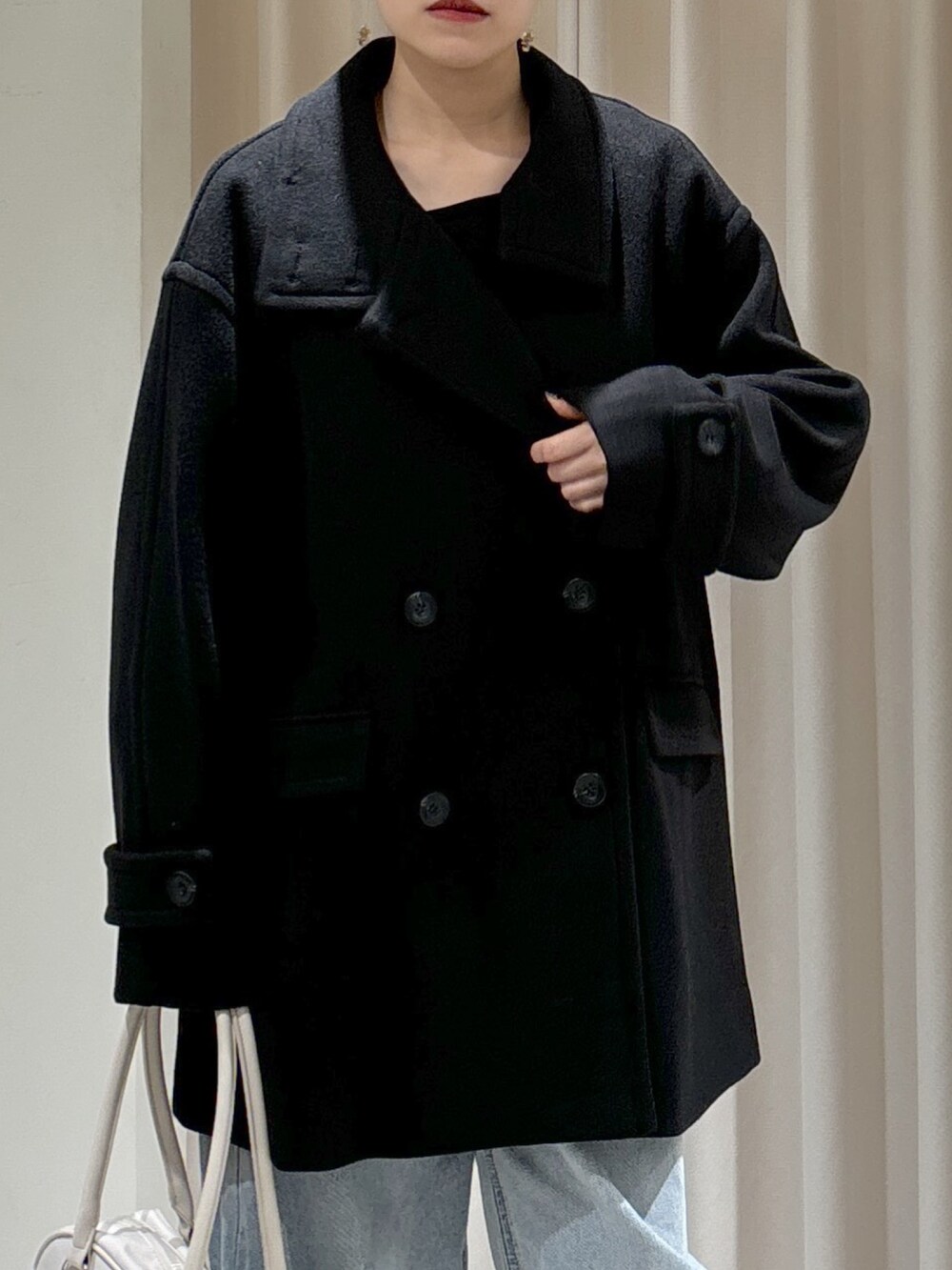 グリーン系のカーディガン/ボレロ、ブルー系のデニムパンツ、ブラック系のハンドバッグを着用したレディースの秋コーディネートの3枚目の写真