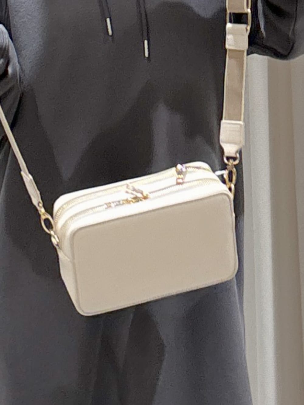 ブラック系のワンピース、ホワイト系のショルダーバッグ、ブラック系のスニーカーを着用したレディースの冬コーディネートの7枚目の写真