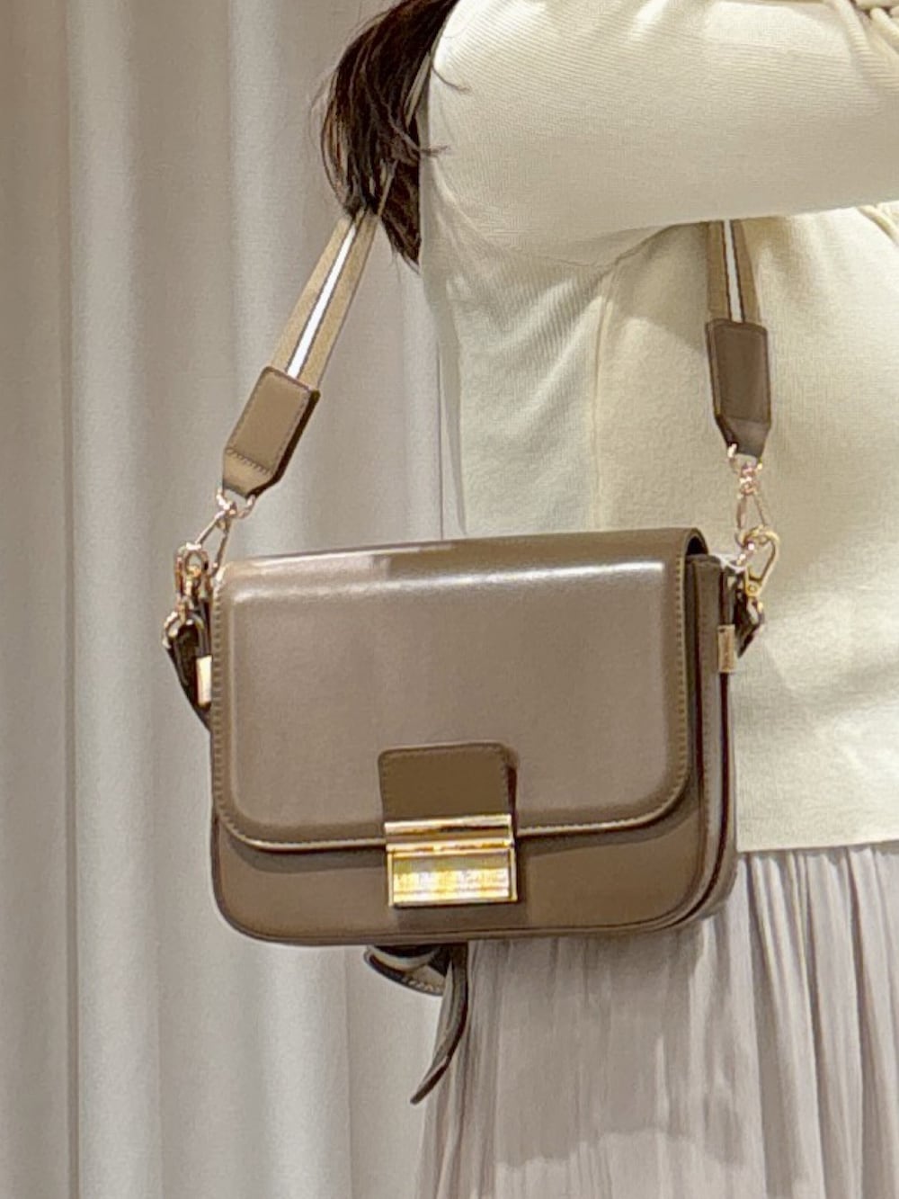 ホワイト系のニット/セーター、ベージュ系のショルダーバッグ、ホワイト系のスカートを着用したレディースの春コーディネートの6枚目の写真