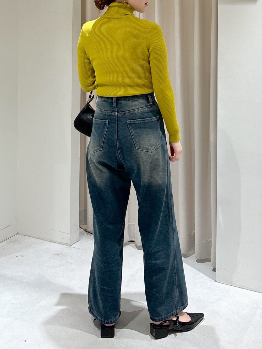 ブラック系のカーディガン/ボレロ、イエロー系のニット/セーター、ブルー系のデニムパンツを着用したレディースの秋コーディネートの6枚目の写真