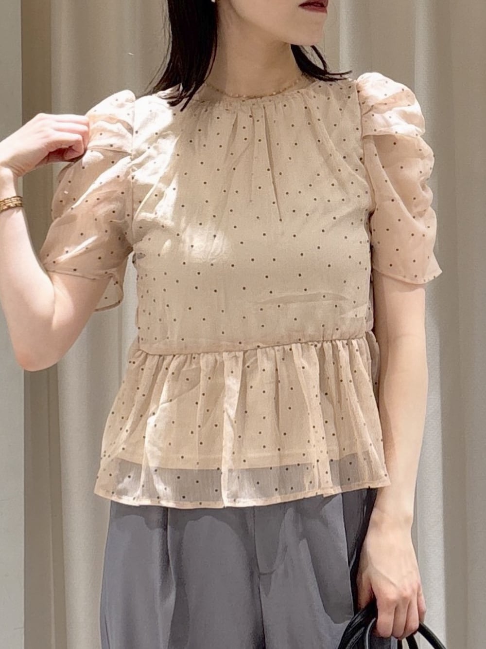 ピンク系のシャツ/ブラウス、ブラック系のハンドバッグ、グレー系のスラックスを着用したレディースの夏コーディネートの4枚目の写真