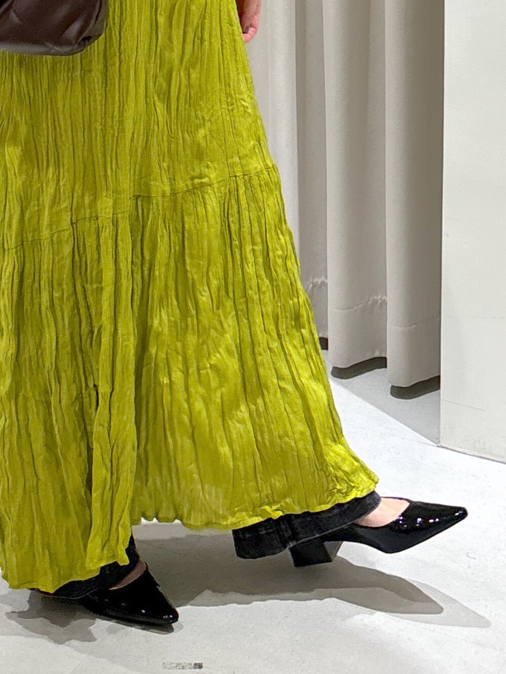 グリーン系のワンピース、ブラウン系のトートバッグ、ブラック系のデニムパンツを着用したレディースの秋コーディネートの8枚目の写真