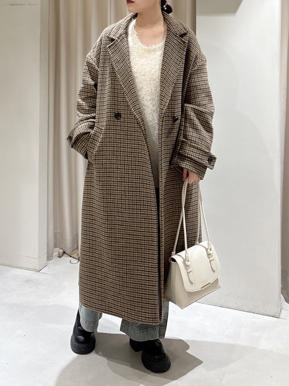 ホワイト系のニット/セーター、ブルー系のデニムパンツ、ホワイト系のショルダーバッグを着用したレディースの冬コーディネートの9枚目の写真
