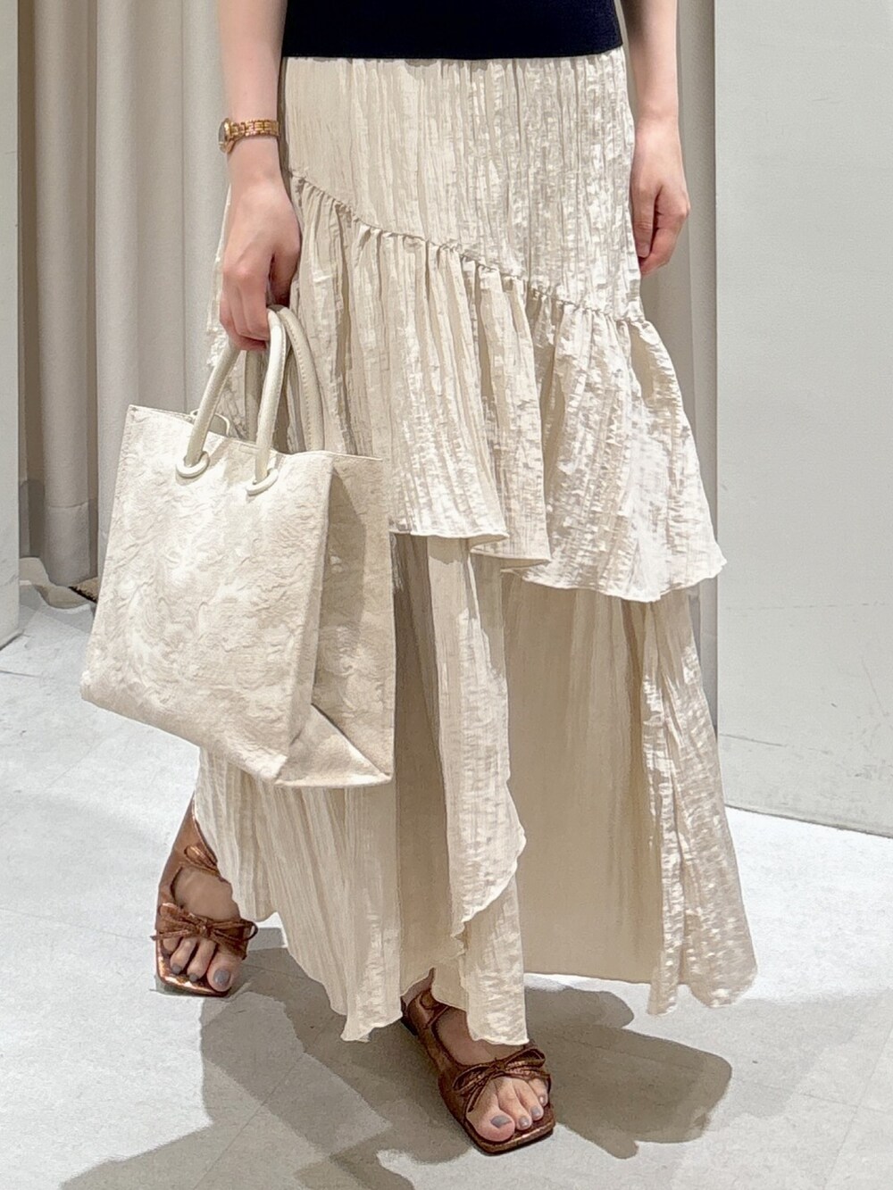 ホワイト系のトートバッグ、ホワイト系のスカート、ブラウン系のサンダルを着用したレディースの夏コーディネートの4枚目の写真