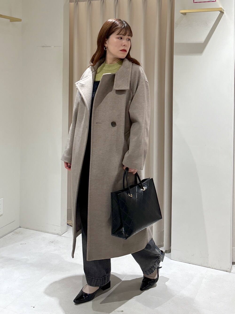 ブラウン系のステンカラーコート、ブラック系のショルダーバッグ、ブラック系のパンプスを着用したレディースの秋コーディネートの2枚目の写真