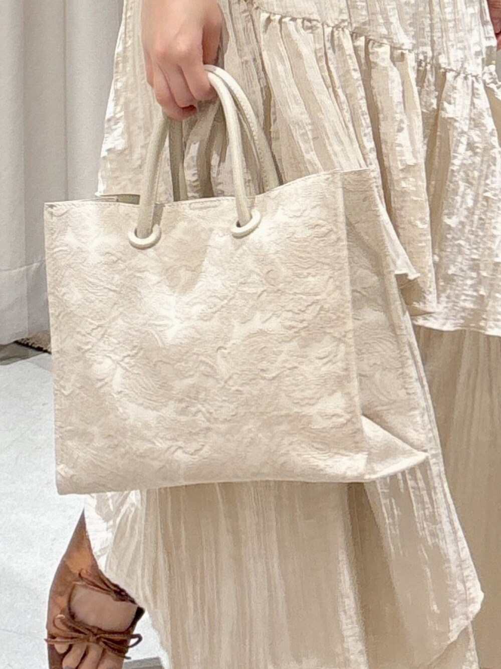 ホワイト系のトートバッグ、ホワイト系のスカート、ブラウン系のサンダルを着用したレディースの夏コーディネートの5枚目の写真