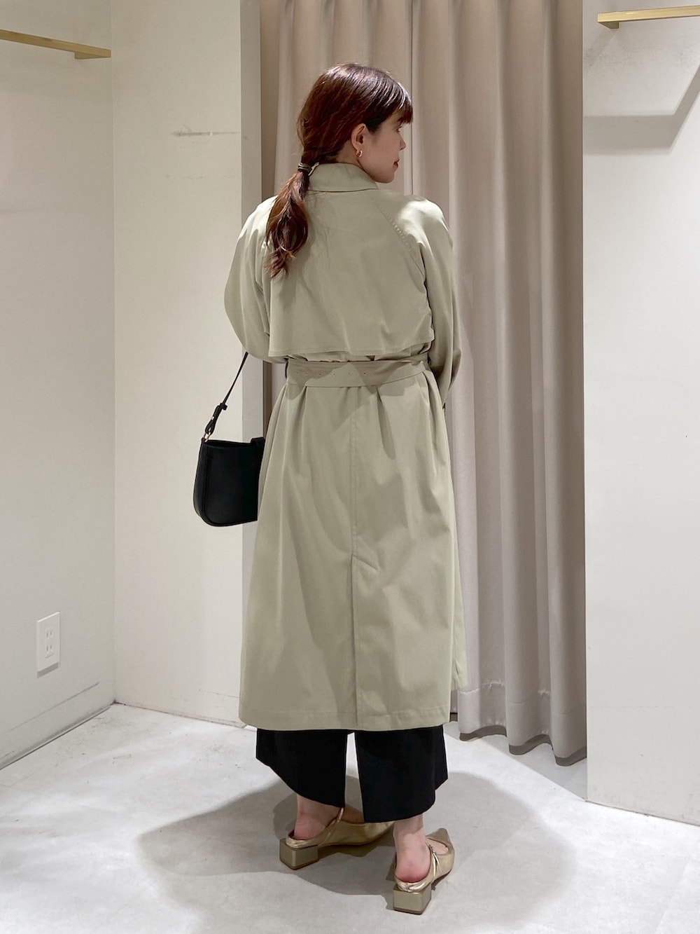 グリーン系のトレンチコート、ブラック系のショルダーバッグ、グリーン系のニット/セーターを着用したレディースの春コーディネートの2枚目の写真