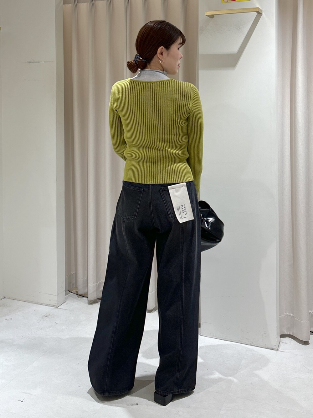 グリーン系のニット/セーター、グレー系のTシャツ/カットソー、ブラック系のハンドバッグを着用したレディースの秋コーディネートの4枚目の写真