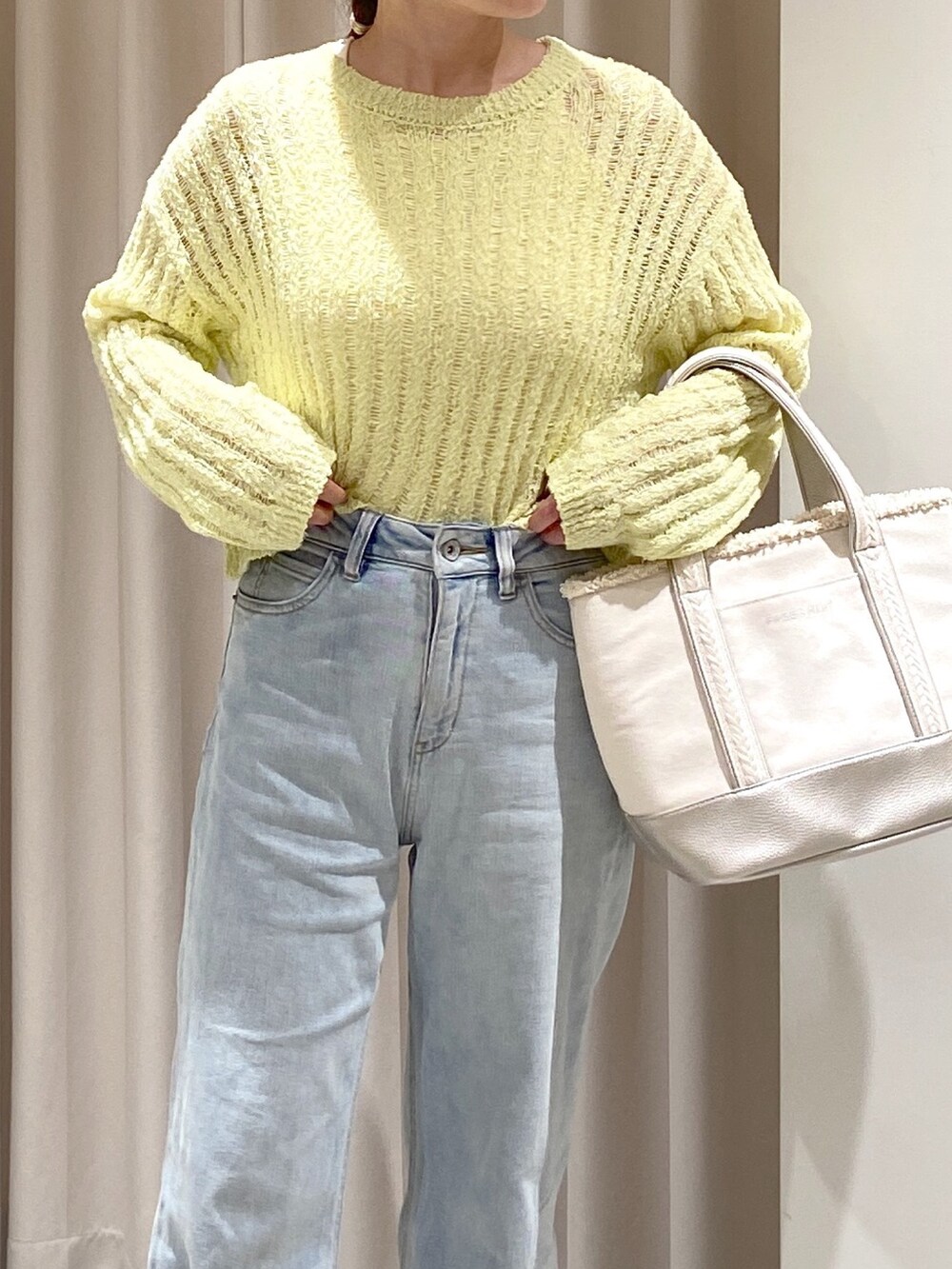 イエロー系のニット/セーター、シルバー系のトートバッグ、ブルー系のデニムパンツを着用したレディースの春コーディネートの4枚目の写真