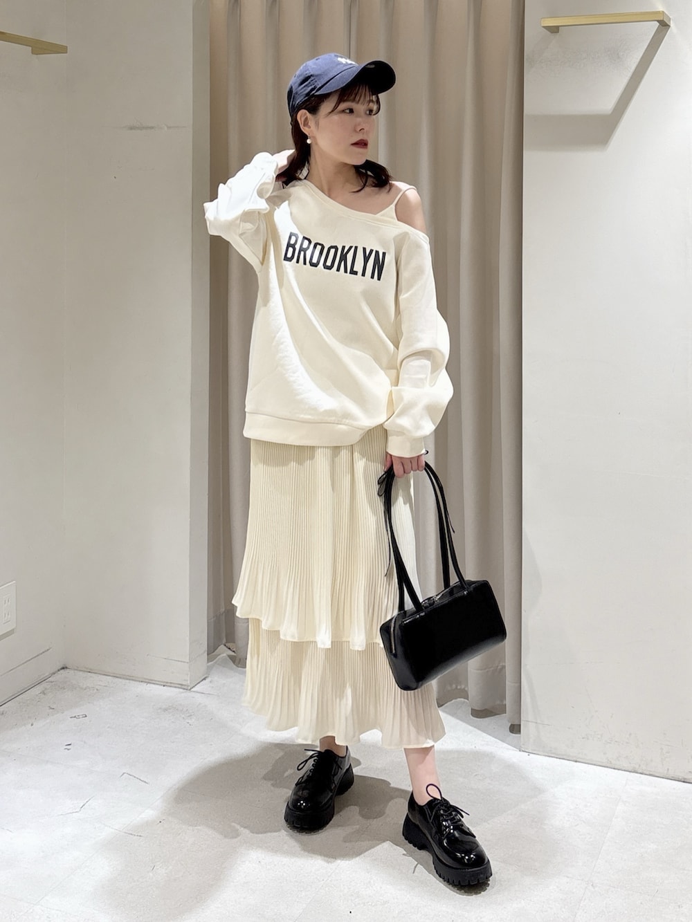 ホワイト系のスウェット、ホワイト系のスカート、ブラック系のショルダーバッグを着用したレディースの春コーディネートの8枚目の写真