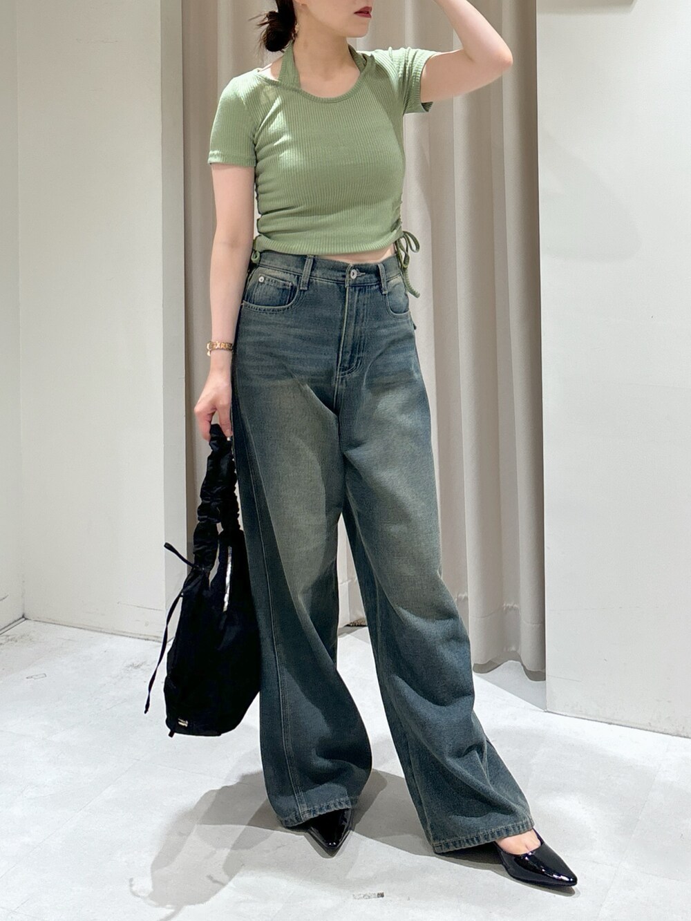 グリーン系のTシャツ/カットソー、ブラック系のパンプス、ブルー系のデニムパンツを着用したレディースの秋コーディネートの4枚目の写真
