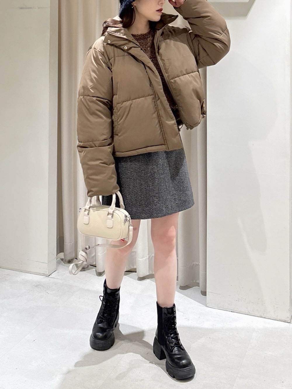 ブラウン系のニット/セーター、ブラック系のスカート、ブラック系のブーツを着用したレディースの冬コーディネートの6枚目の写真