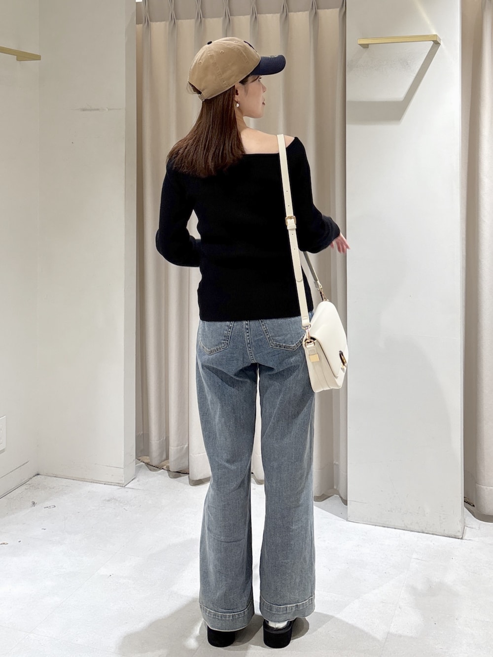 ブラック系のニット/セーター、ホワイト系のハンドバッグ、ブルー系のデニムパンツを着用したレディースの冬コーディネートの4枚目の写真