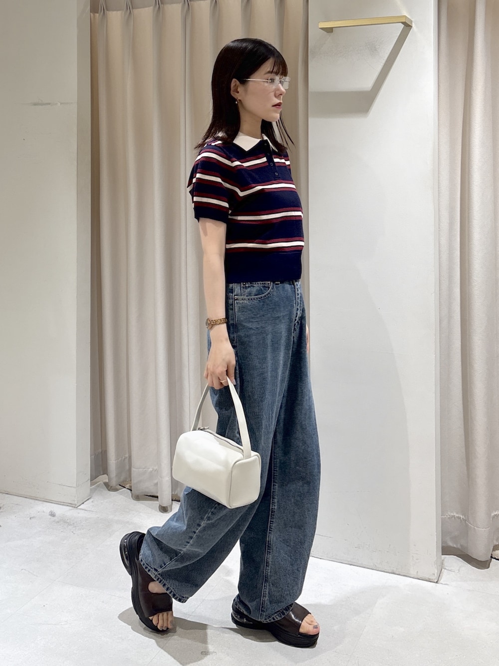 ブルー系のニット/セーター、ホワイト系のハンドバッグ、ブルー系のデニムパンツを着用したレディースの夏コーディネートの5枚目の写真