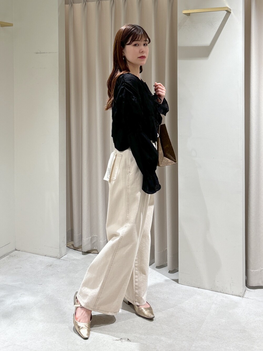 ブラウン系のトートバッグ、ホワイト系のデニムパンツ、ゴールド系のパンプスを着用したレディースの春コーディネートの6枚目の写真