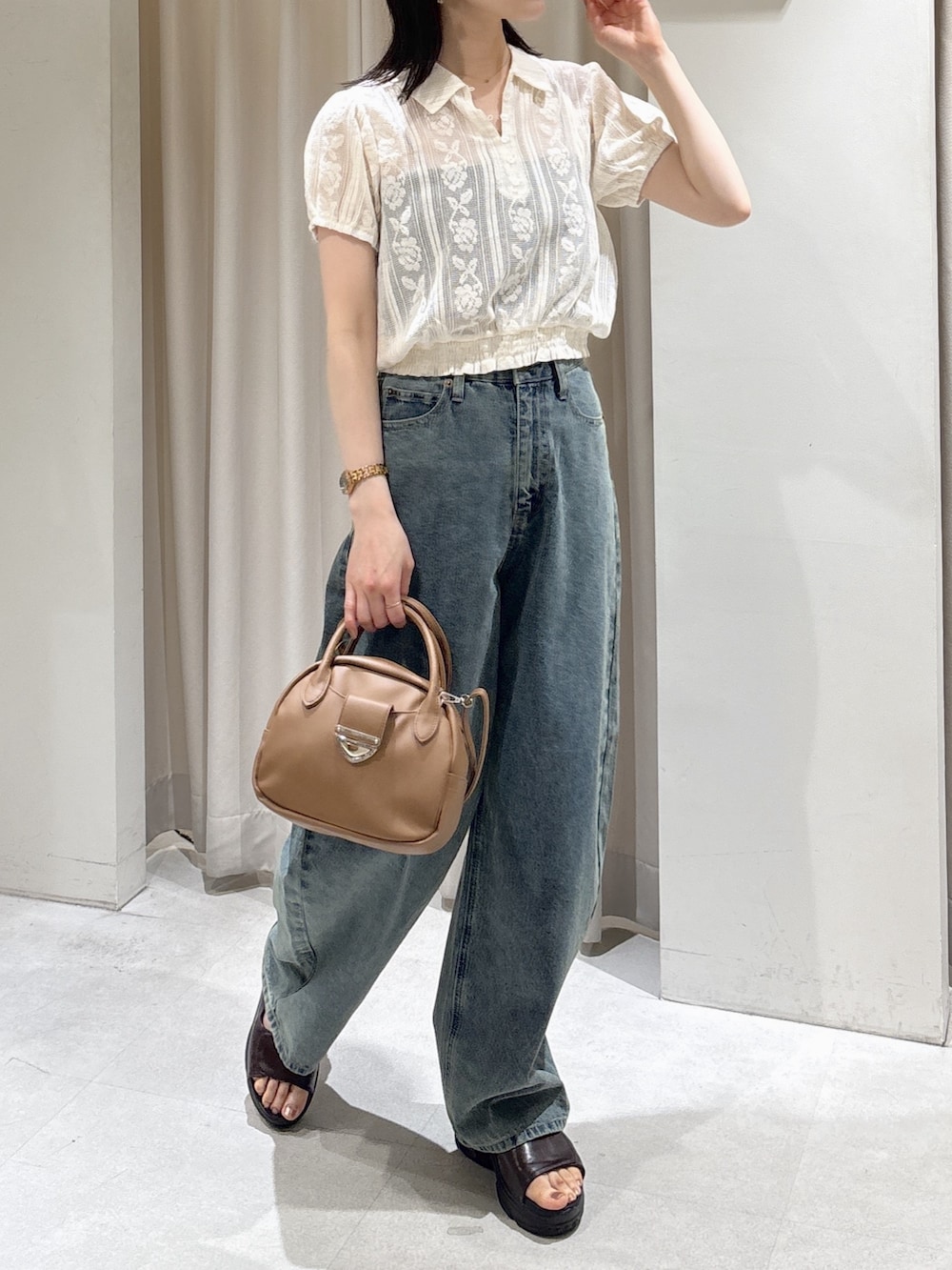 ホワイト系のシャツ/ブラウス、ブラウン系のハンドバッグ、ブルー系のデニムパンツを着用したレディースの夏コーディネートの6枚目の写真