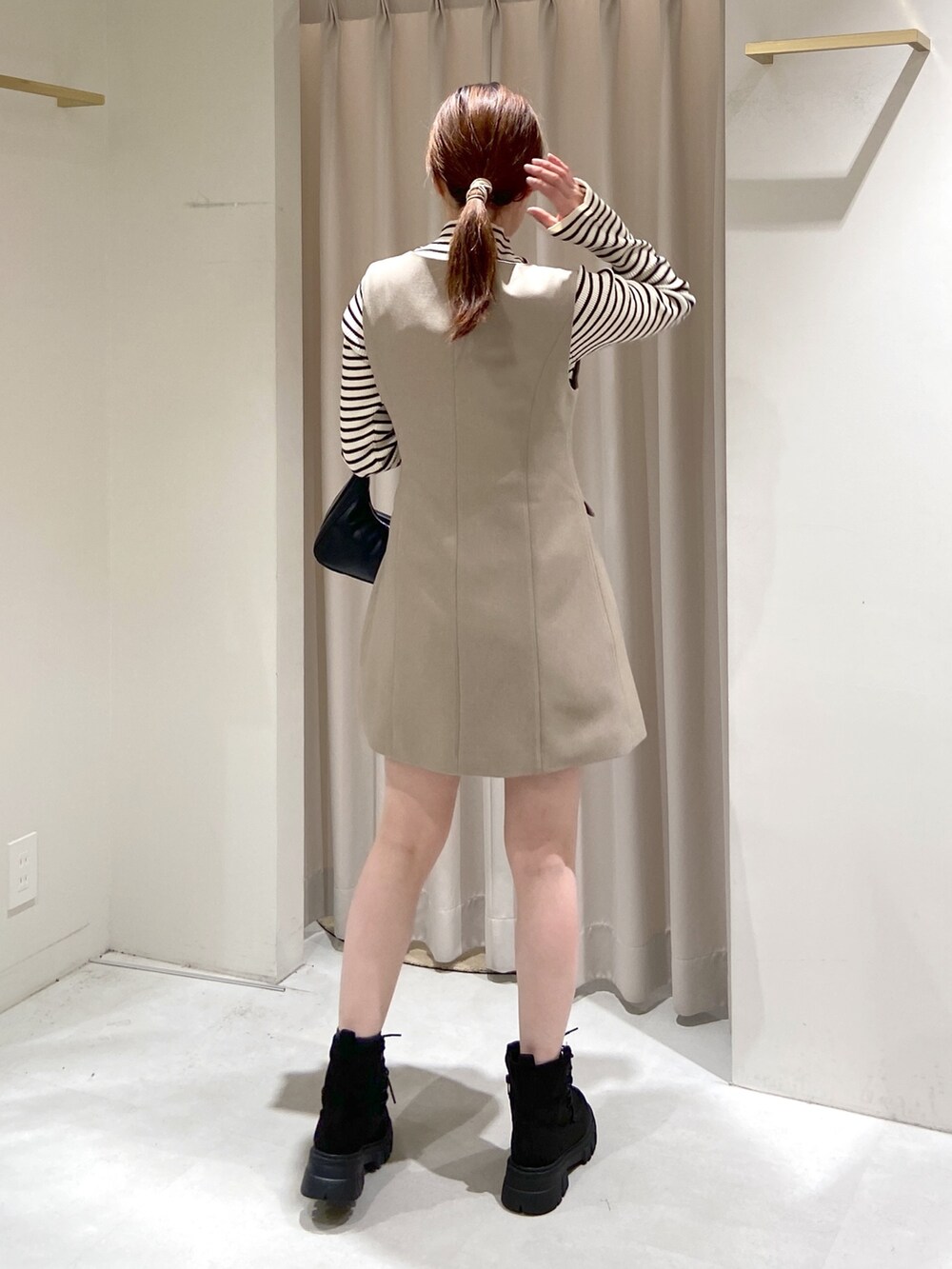 ベージュ系のワンピース、ホワイト系のニット/セーター、ブラック系のショルダーバッグを着用したレディースの冬コーディネートの5枚目の写真