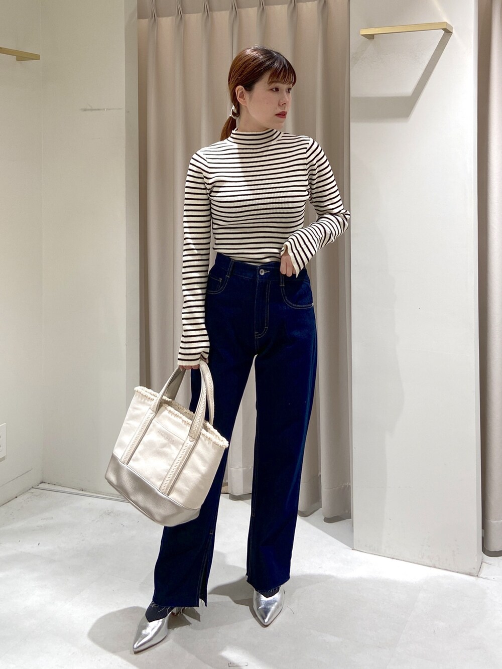 ホワイト系のニット/セーター、ブルー系のベスト、ブルー系のデニムパンツを着用したレディースの冬コーディネートの6枚目の写真