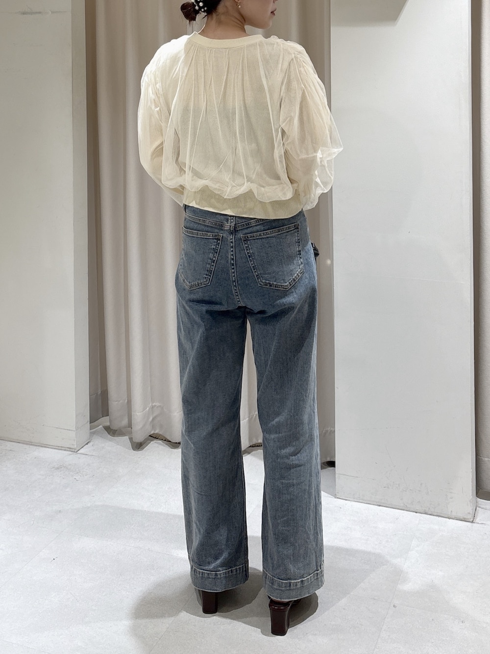 イエロー系のニット/セーター、ブルー系のデニムパンツ、ブラック系のショルダーバッグを着用したレディースの冬コーディネートの4枚目の写真