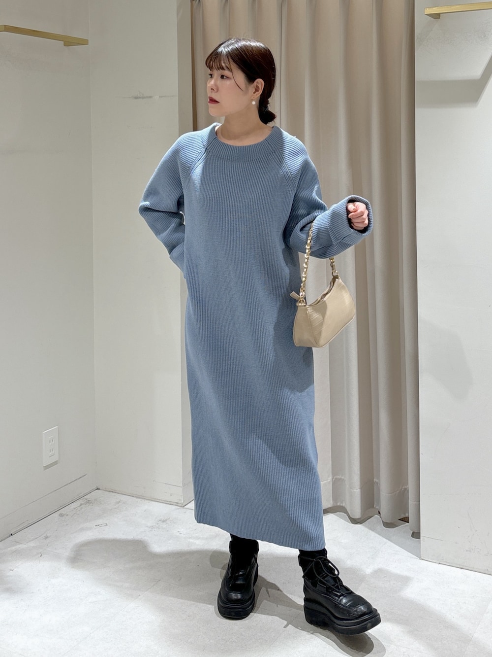 ブルー系のワンピース、ベージュ系のトートバッグ、ブラック系のブーツを着用したレディースの冬コーディネートの2枚目の写真