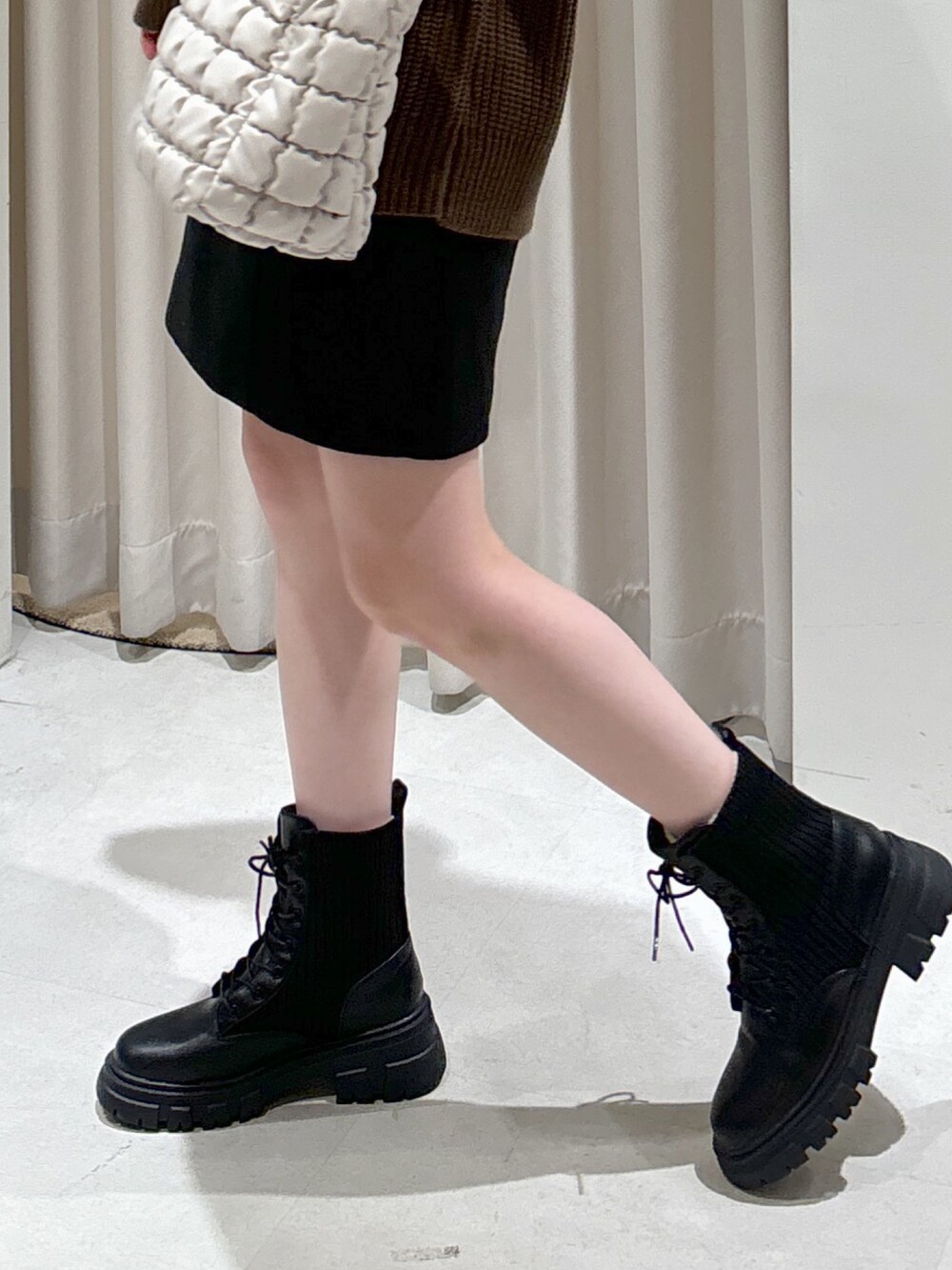 ブラウン系のニット/セーター、ホワイト系のハンドバッグ、ブラック系のスカートを着用したレディースの秋コーディネートの4枚目の写真