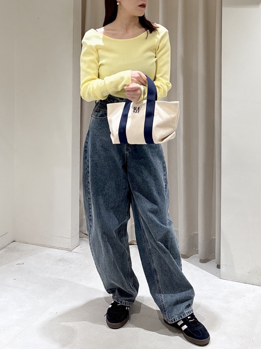 ブラック系のノーカラージャケット、イエロー系のニット/セーター、ブルー系のデニムパンツを着用したレディースの冬コーディネートの5枚目の写真