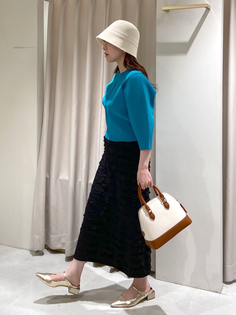 ブラック系のスカート、ブルー系のニット/セーター、ブラウン系のショルダーバッグを着用したレディースの春コーディネートの6枚目の写真