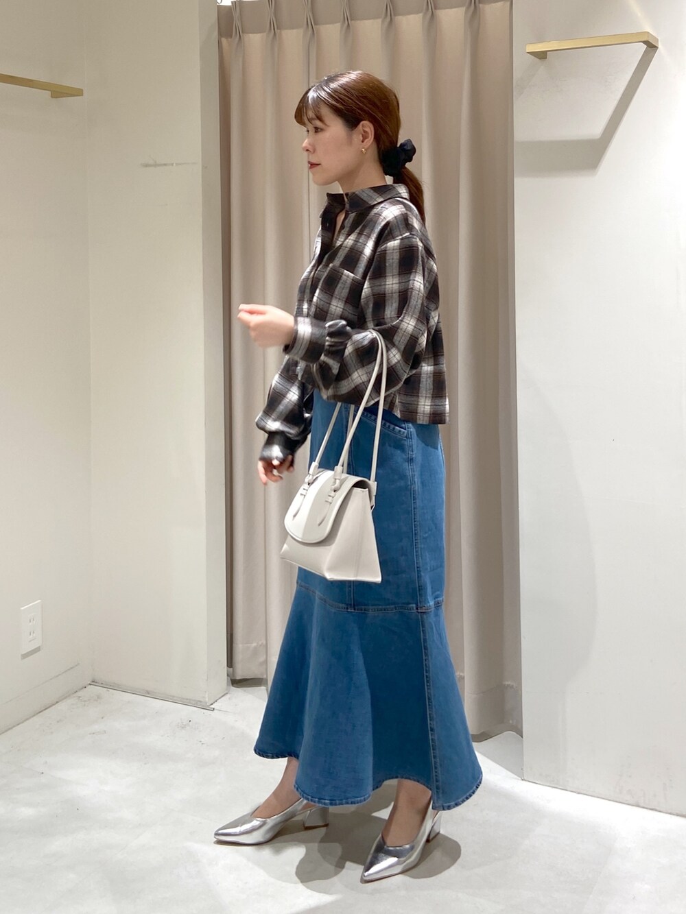 ブラウン系のシャツ/ブラウス、ブルー系のデニムスカート、ホワイト系のショルダーバッグを着用したレディースの冬コーディネートの2枚目の写真
