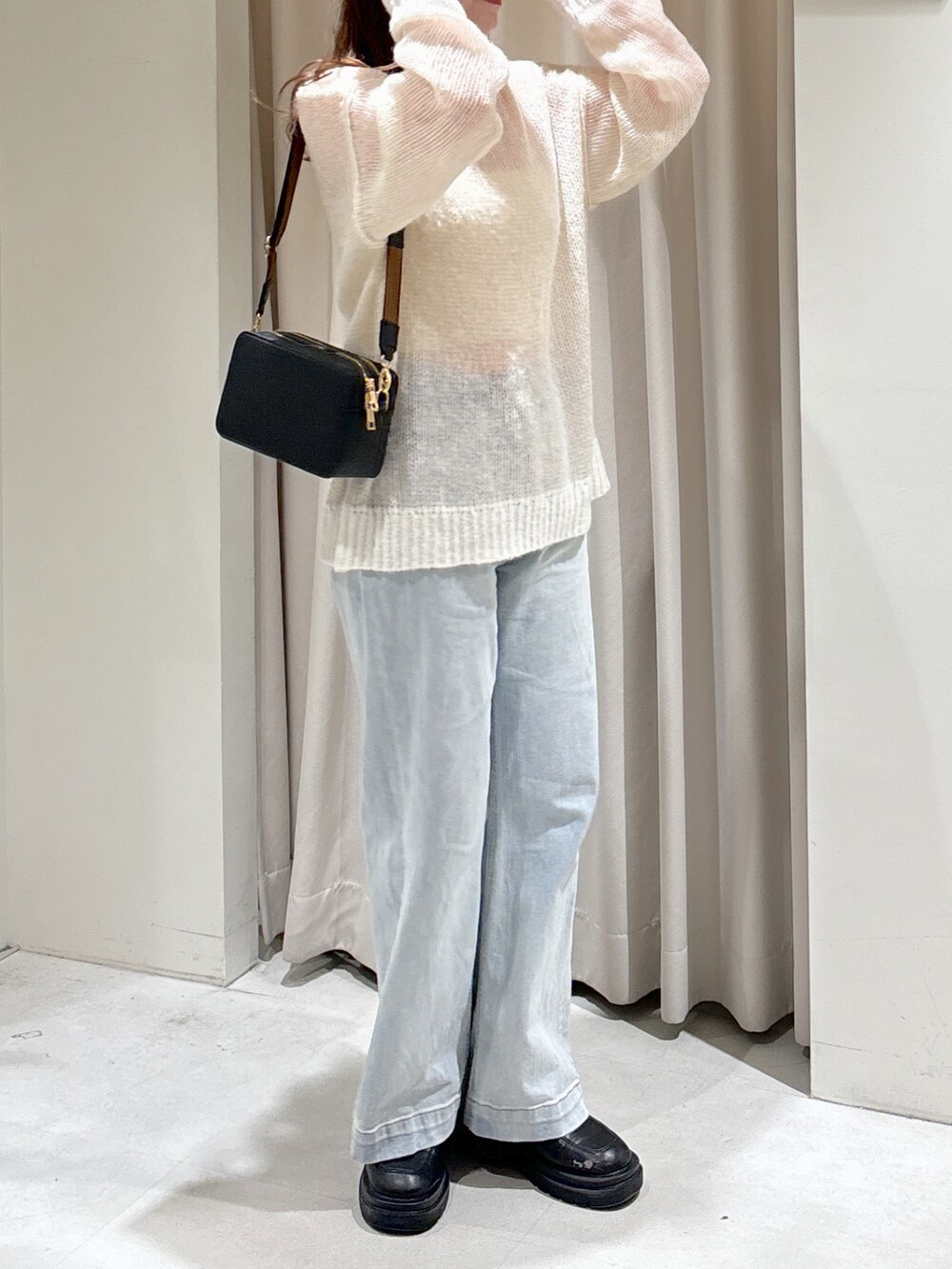 ホワイト系のニット/セーター、ブラック系のショルダーバッグ、ブルー系のデニムパンツを着用したレディースの冬コーディネートの6枚目の写真