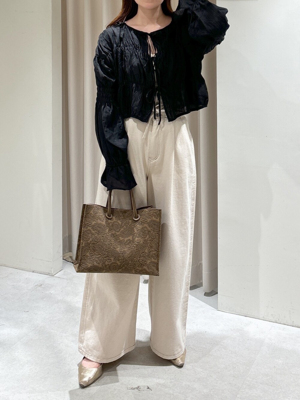 ブラウン系のトートバッグ、ホワイト系のデニムパンツ、ゴールド系のパンプスを着用したレディースの春コーディネートの2枚目の写真