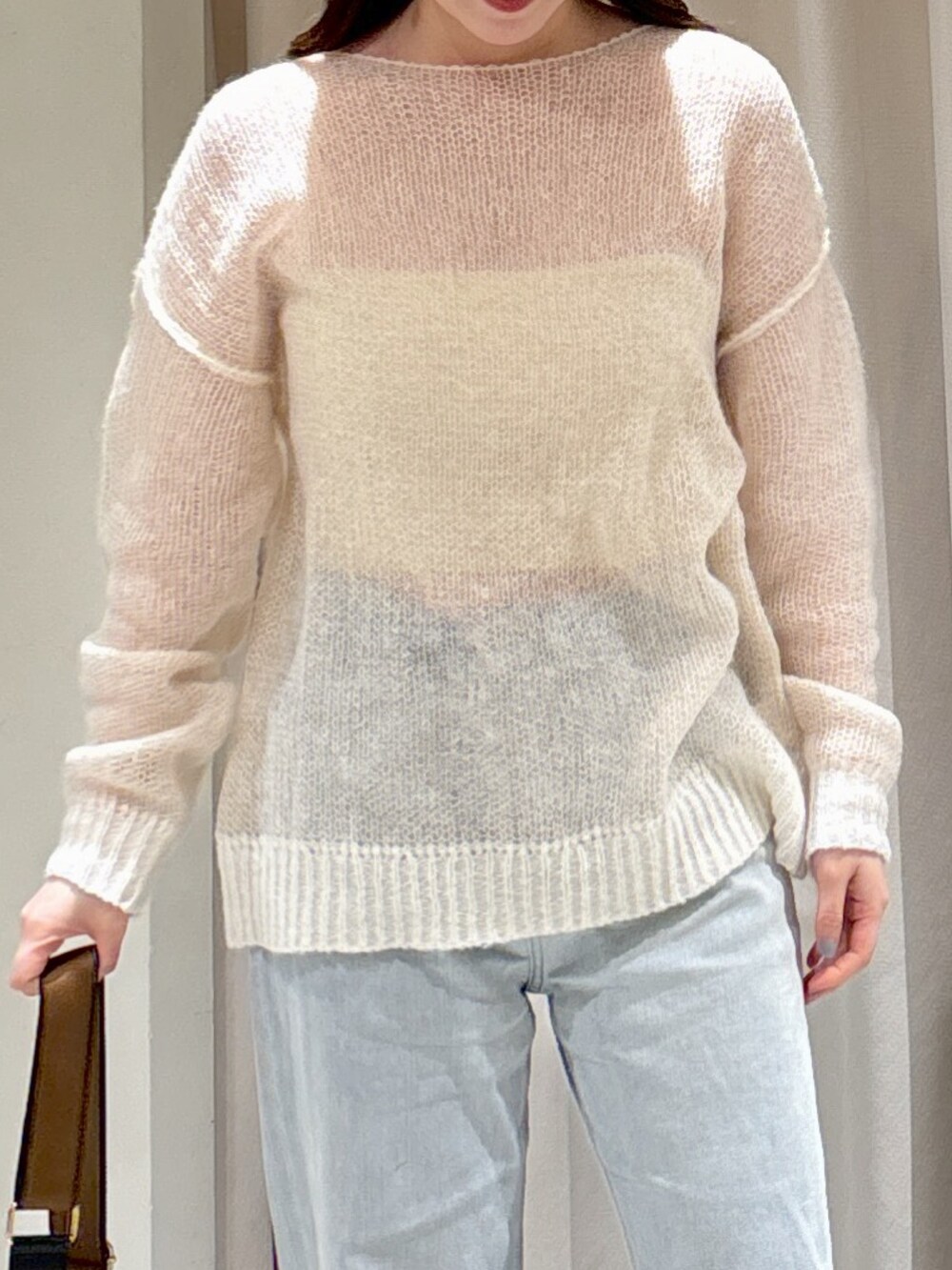 ホワイト系のニット/セーター、ブラック系のショルダーバッグ、ブルー系のデニムパンツを着用したレディースの冬コーディネートの5枚目の写真