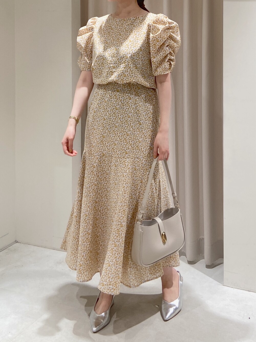 イエロー系のワンピース、グレー系のショルダーバッグ、シルバー系のパンプスを着用したレディースの春コーディネートの6枚目の写真