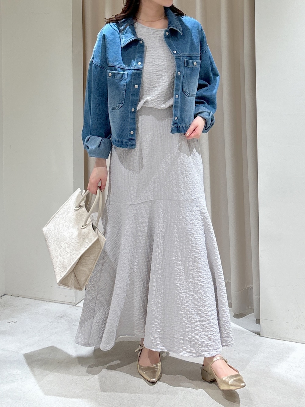 ブルー系のブルゾン、グレー系のワンピース、ホワイト系のトートバッグを着用したレディースの春コーディネートの3枚目の写真