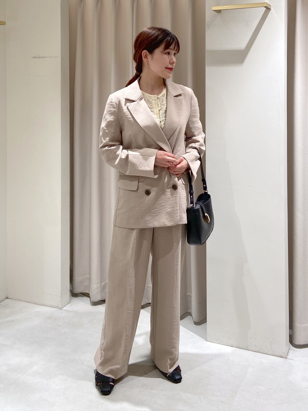 ベージュ系のテーラードジャケット、ホワイト系のスラックス、ホワイト系のカーディガン/ボレロを着用したレディースの春コーディネートの3枚目の写真