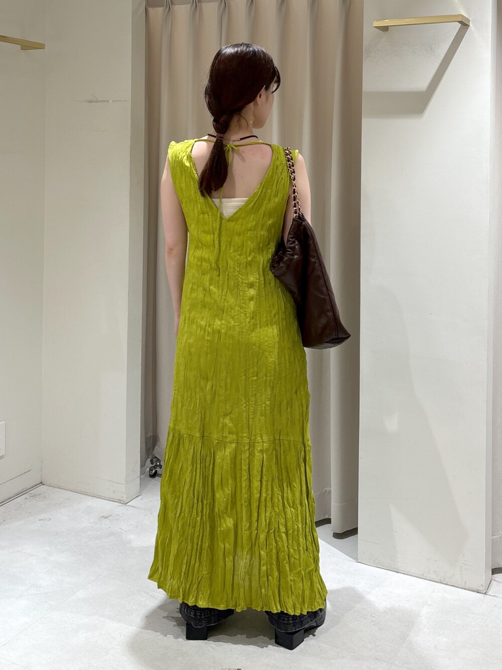 グリーン系のワンピース、ブラウン系のトートバッグ、ブラック系のデニムパンツを着用したレディースの秋コーディネートの5枚目の写真