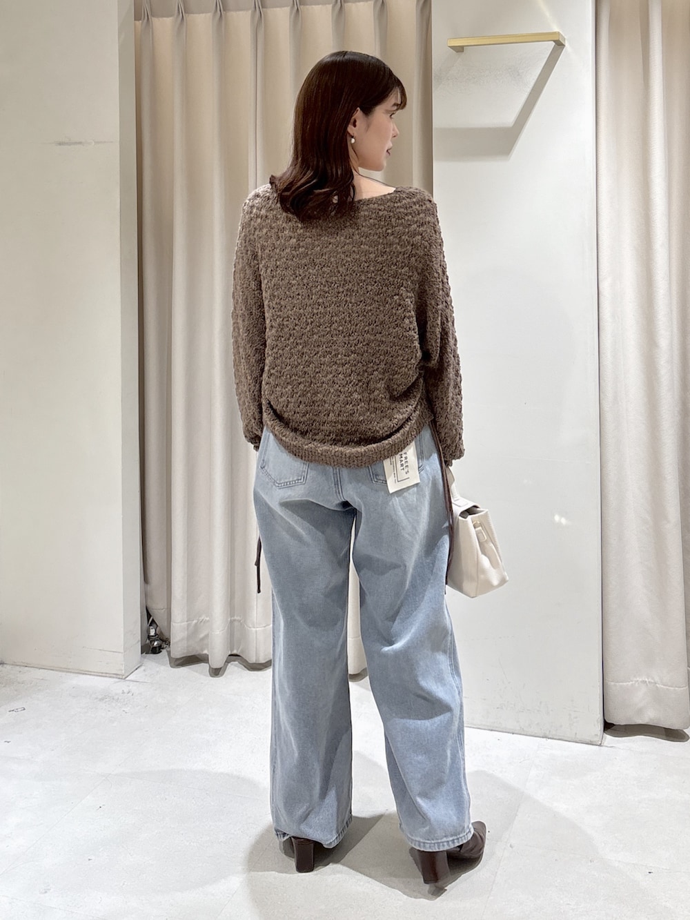 ブラウン系のニット/セーター、ホワイト系のショルダーバッグ、ブルー系のデニムパンツを着用したレディースの冬コーディネートの3枚目の写真