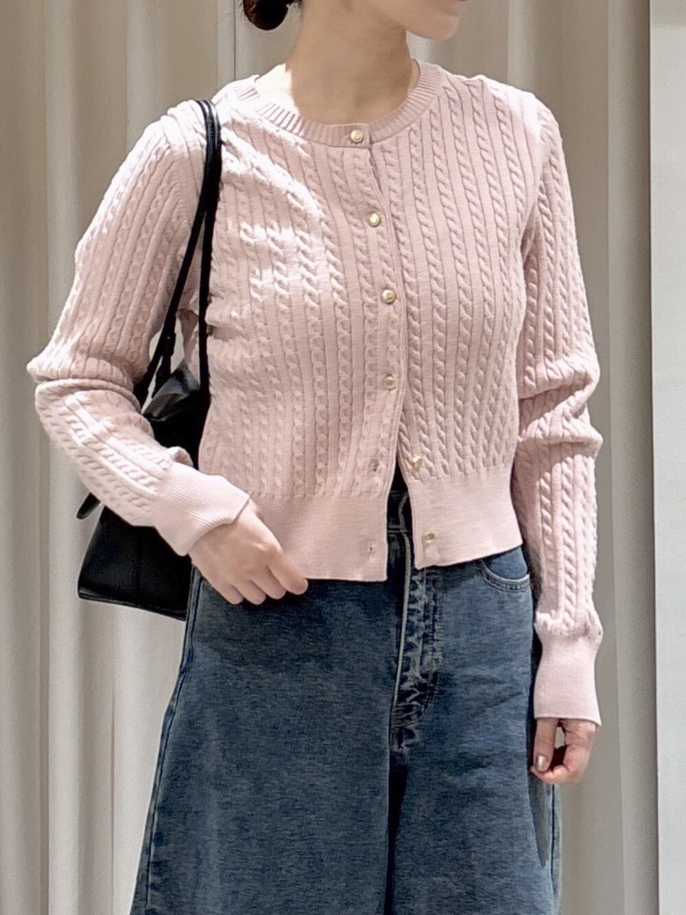 ピンク系のニット/セーター、ブラック系のショルダーバッグ、ブルー系のデニムパンツを着用したレディースの冬コーディネートの2枚目の写真