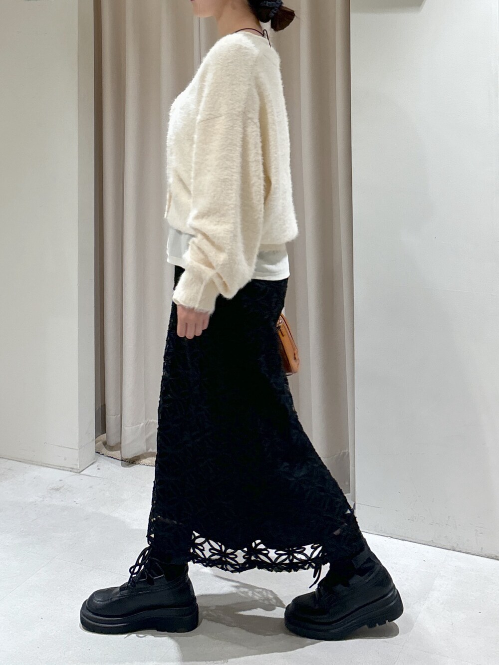 ブラック系のスカート、ベージュ系のショルダーバッグ、ブラック系のブーツを着用したレディースの冬コーディネートの4枚目の写真