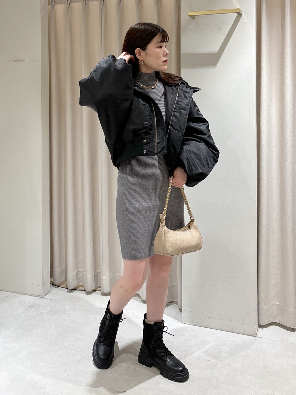 グレー系のワンピース、ベージュ系のトートバッグ、ブラック系のブーツを着用したレディースの秋コーディネートの6枚目の写真