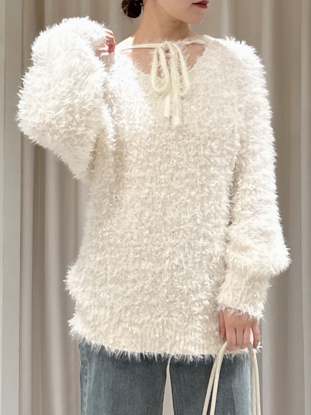 ホワイト系のニット/セーター、ブルー系のデニムパンツ、ホワイト系のショルダーバッグを着用したレディースの冬コーディネートの5枚目の写真