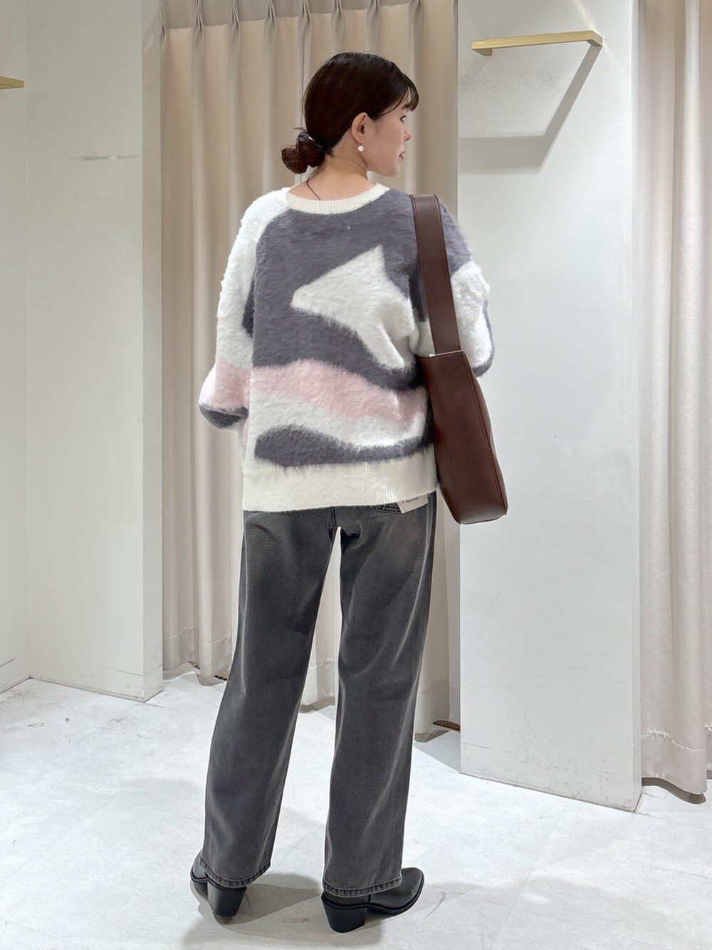 ホワイト系のニット/セーター、ブラウン系のトートバッグ、ブラック系のデニムパンツを着用したレディースの冬コーディネートの6枚目の写真