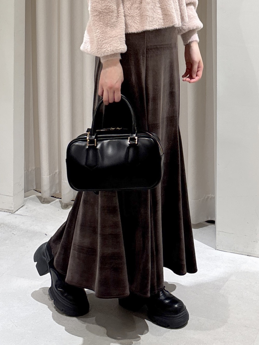 ピンク系のニット/セーター、ブラウン系のスカート、ブラック系のブーツを着用したレディースの冬コーディネートの4枚目の写真