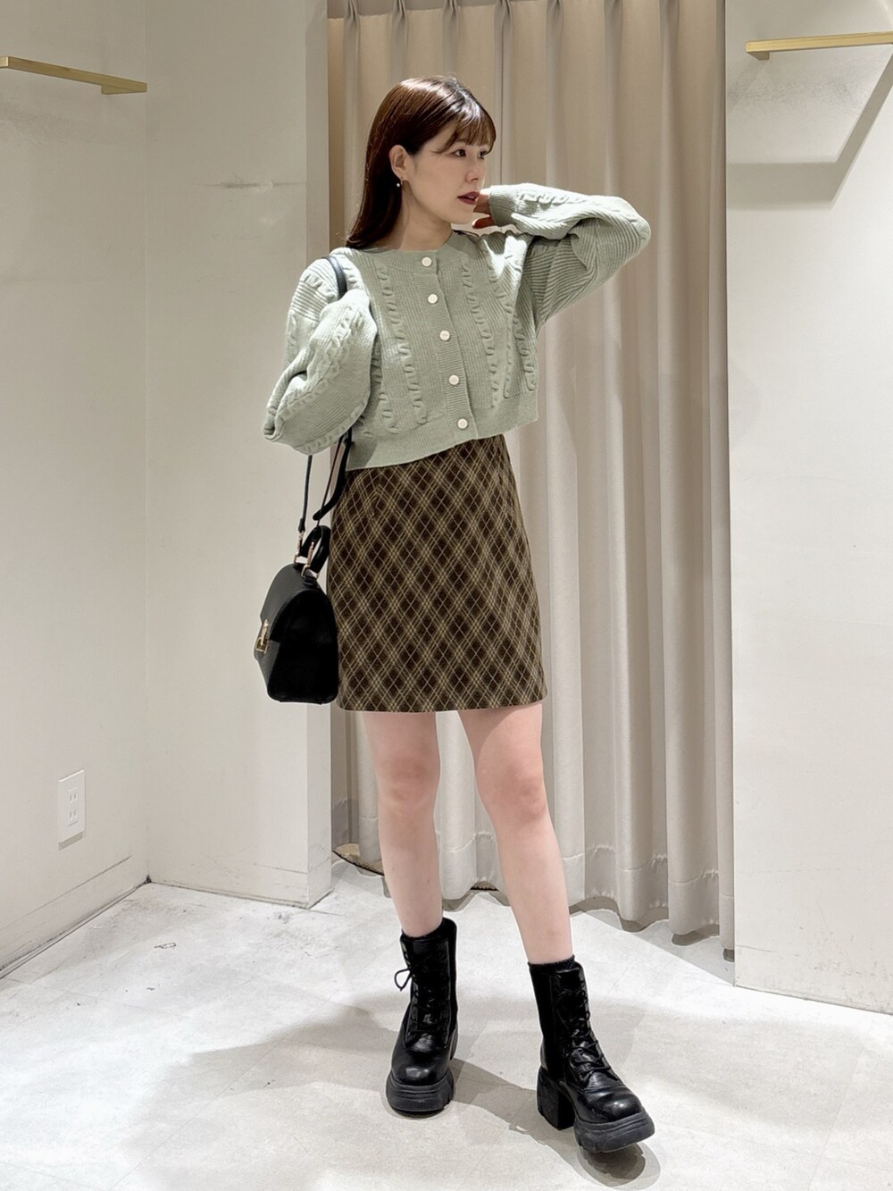 グリーン系のワンピース、ブラウン系のスカート、ブラック系のトートバッグを着用したレディースの冬コーディネートの2枚目の写真