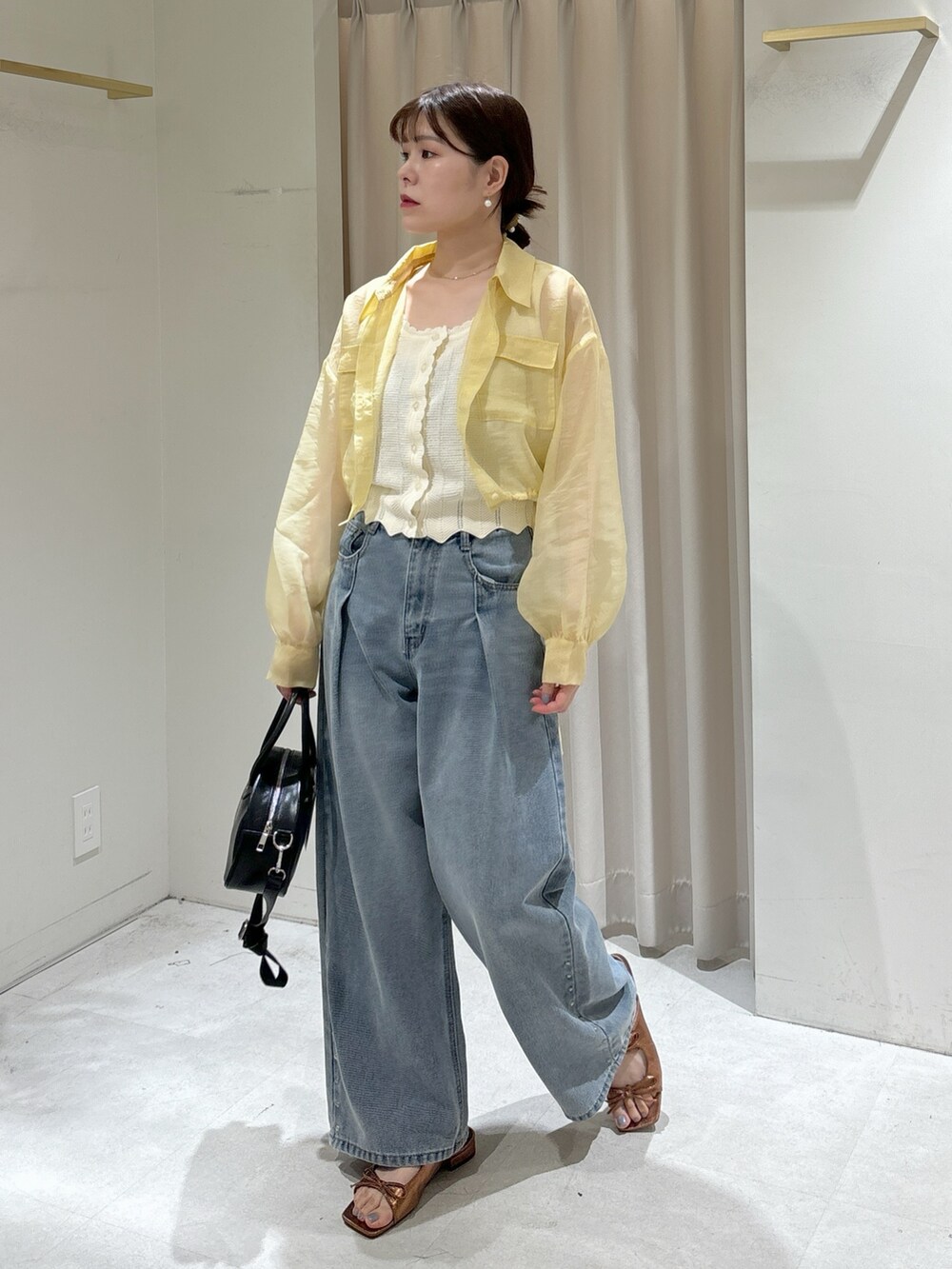 イエロー系のシャツ/ブラウス、ホワイト系のニット/セーター、ブルー系のデニムパンツを着用したレディースの春コーディネートの2枚目の写真