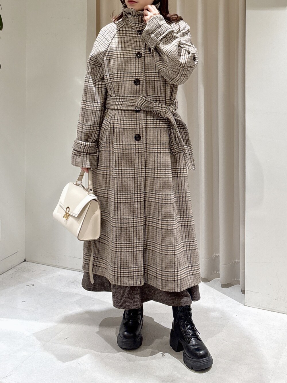 イエロー系のニット/セーター、ブラウン系のスカート、ブラック系のブーツを着用したレディースの秋コーディネートの6枚目の写真