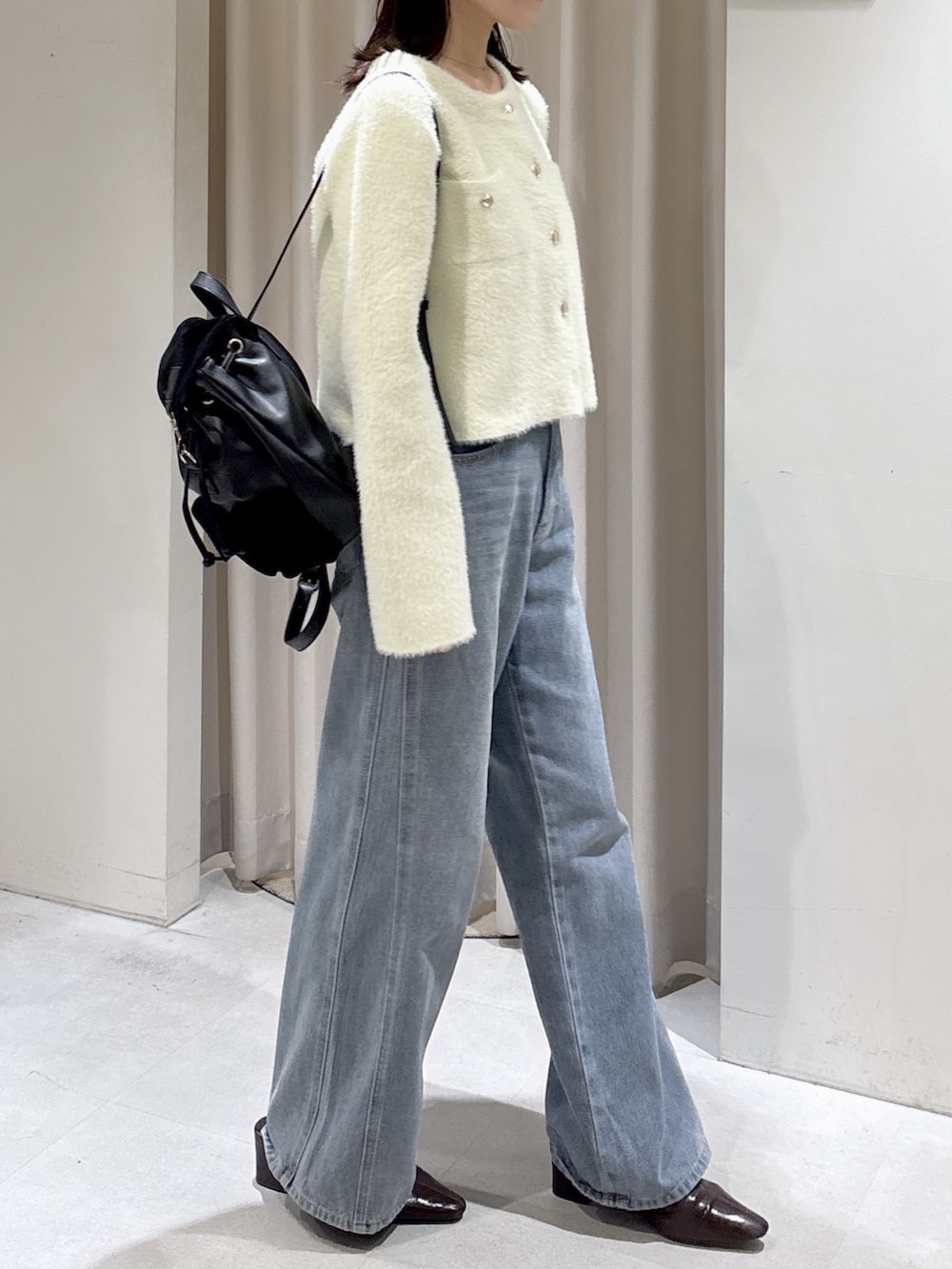 イエロー系のニット/セーター、ブルー系のデニムパンツ、ブラック系のバックパック/リュックを着用したレディースの秋コーディネートの2枚目の写真
