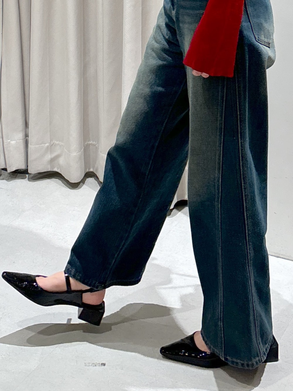 レッド系のニット/セーター、ブルー系のデニムパンツ、ブラック系のショルダーバッグを着用したレディースの秋コーディネートの6枚目の写真