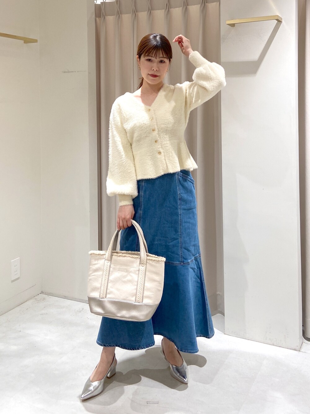 ホワイト系のカーディガン/ボレロ、ブルー系のデニムスカート、シルバー系のパンプスを着用したレディースの冬コーディネートの5枚目の写真